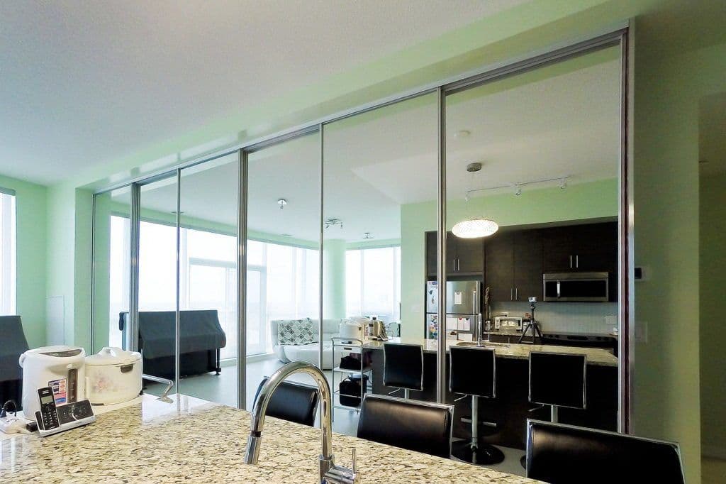Completed Roomidea glass room divider separating a kitchen and living area