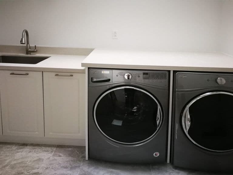 Completed Roomidea laundry room cabinetry installed above and beside a washer and dryer