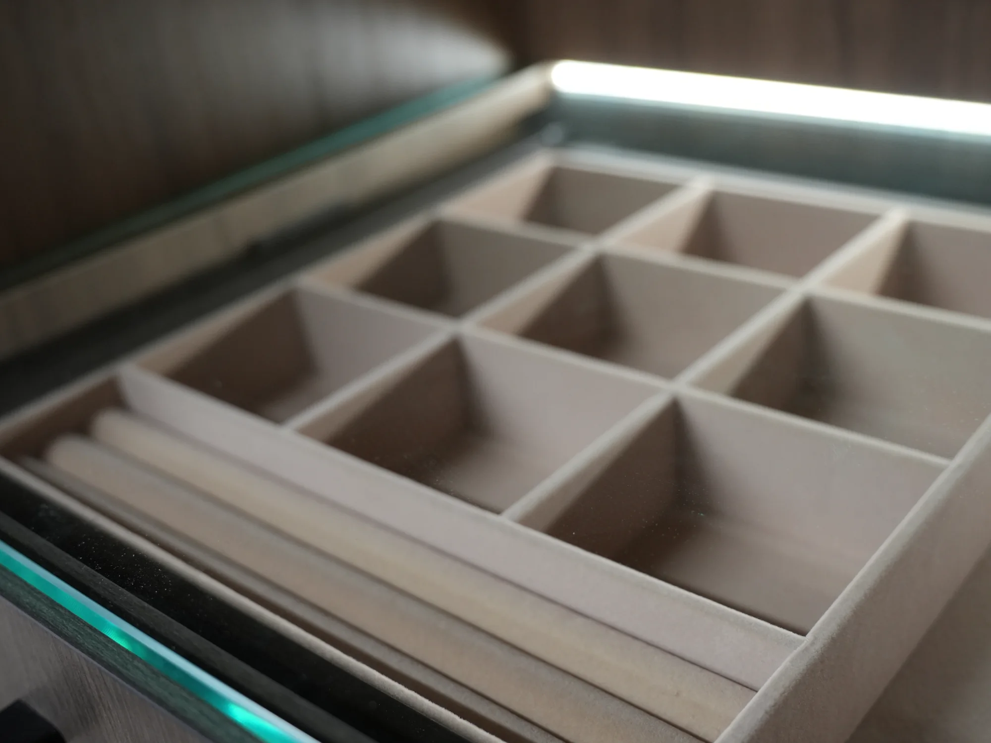 Fitted illuminated jewelry tray with divided storage compartments.