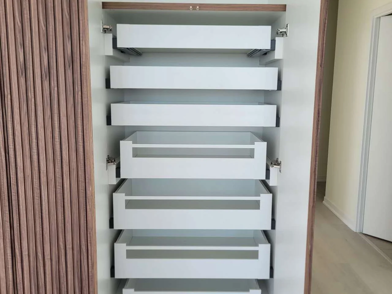 Installed tall pantry cabinet with multiple pull-out storage trays.