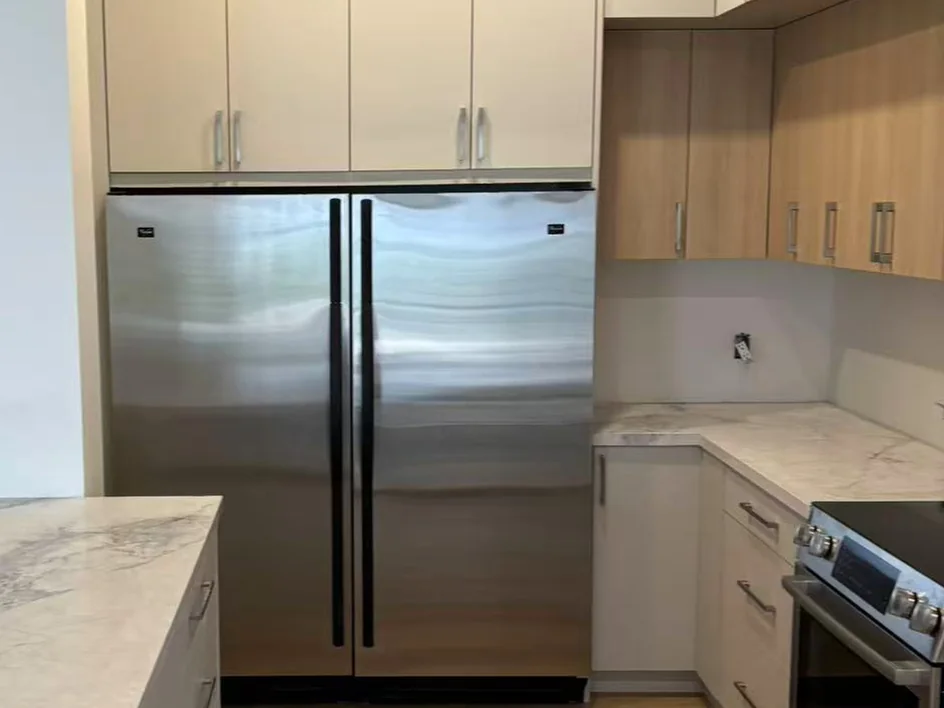 Installed layered cabinet storage around a full-height refrigerator opening.
