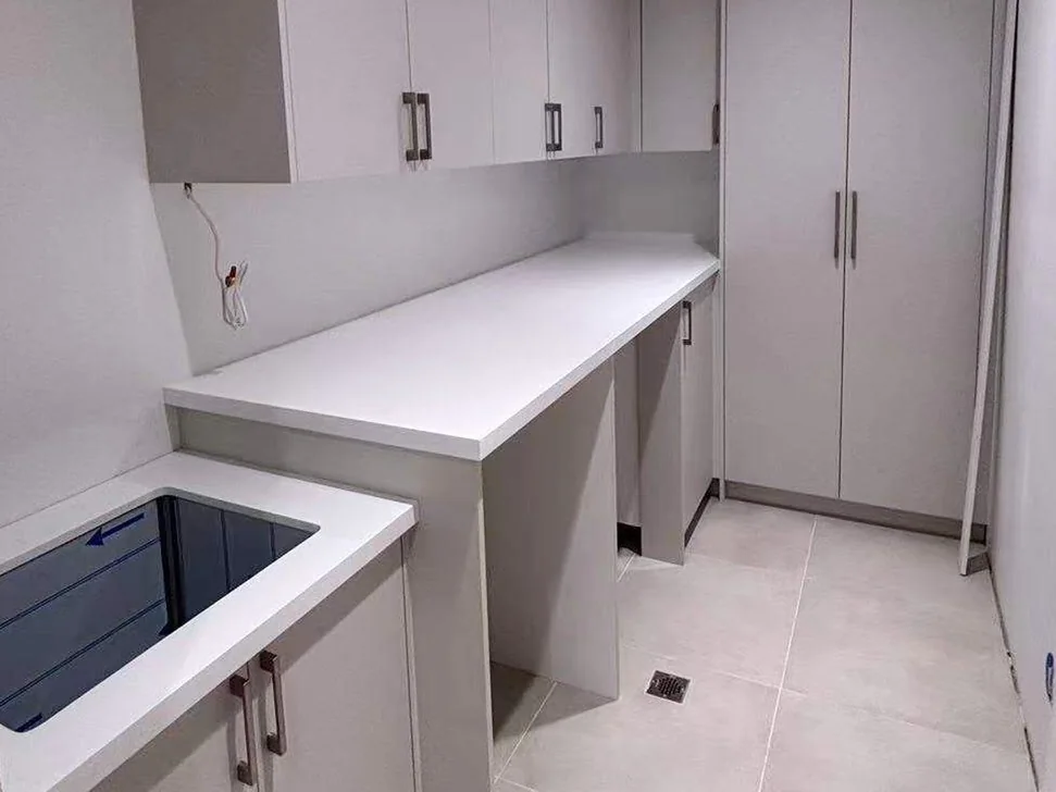 Completed L-shaped laundry cabinetry with tall storage and a long work surface.