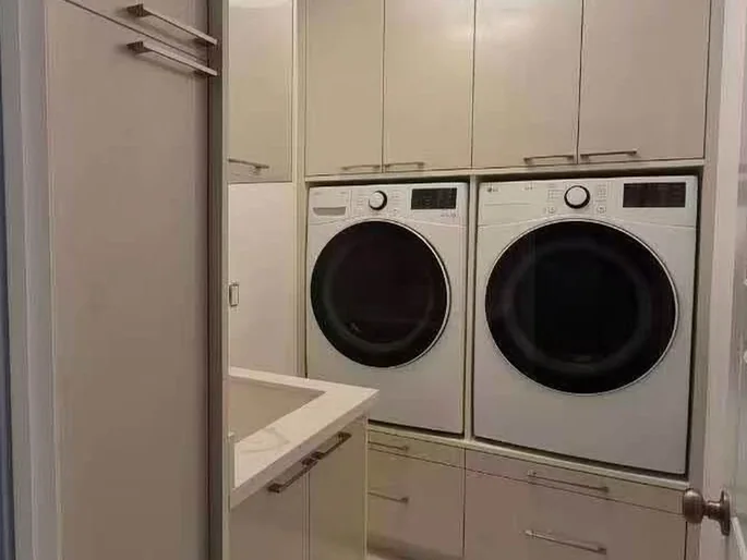 Completed laundry storage fitted around stacked appliances.