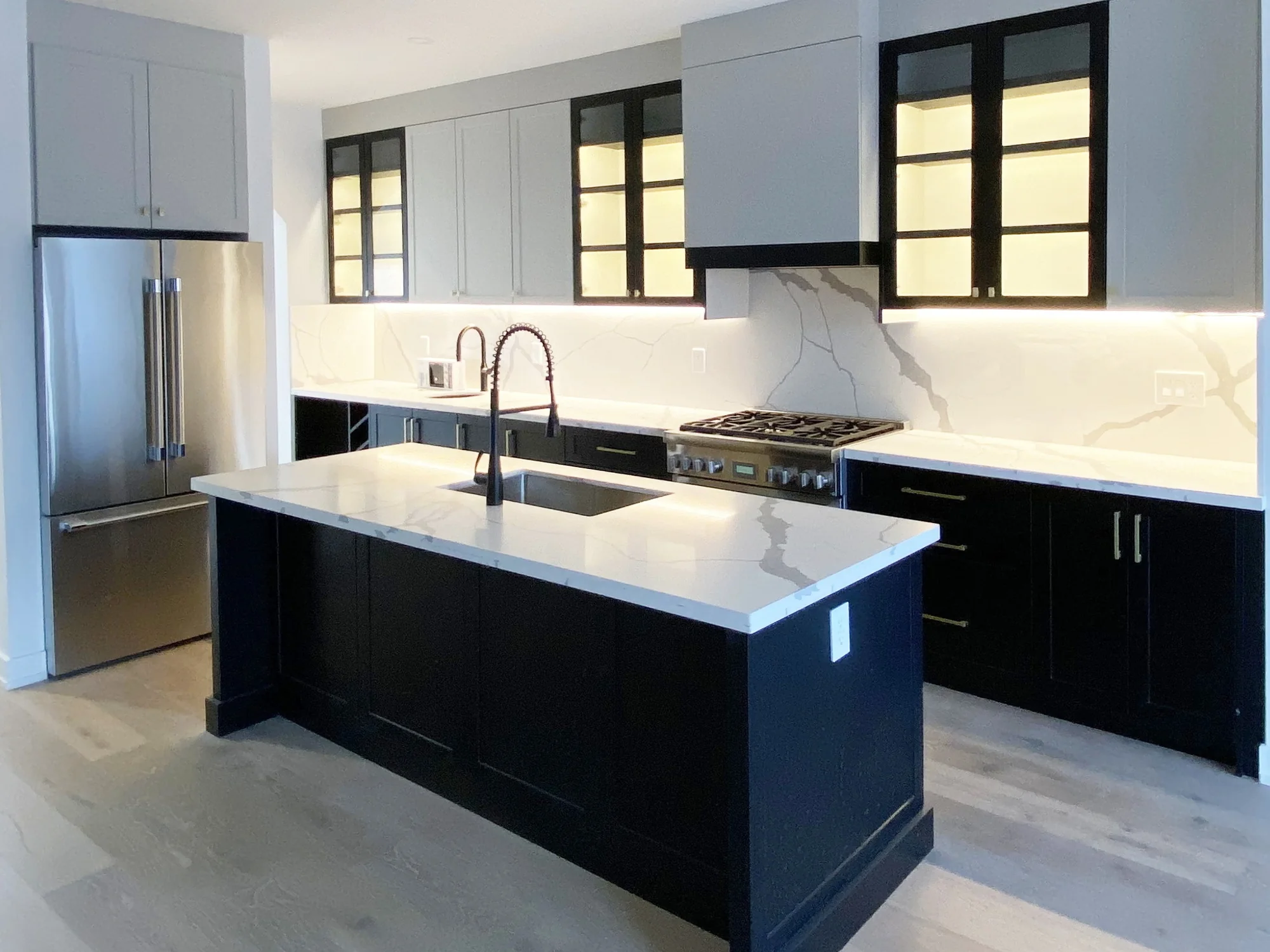 Completed black-and-white kitchen with framed lower cabinets, black-framed glass uppers, and a clean contemporary contrast.