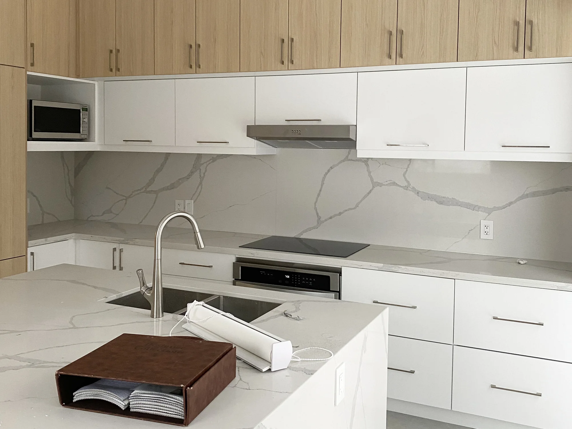 Completed Modern kitchen with white and light-wood flat-panel cabinetry and restrained hardware.