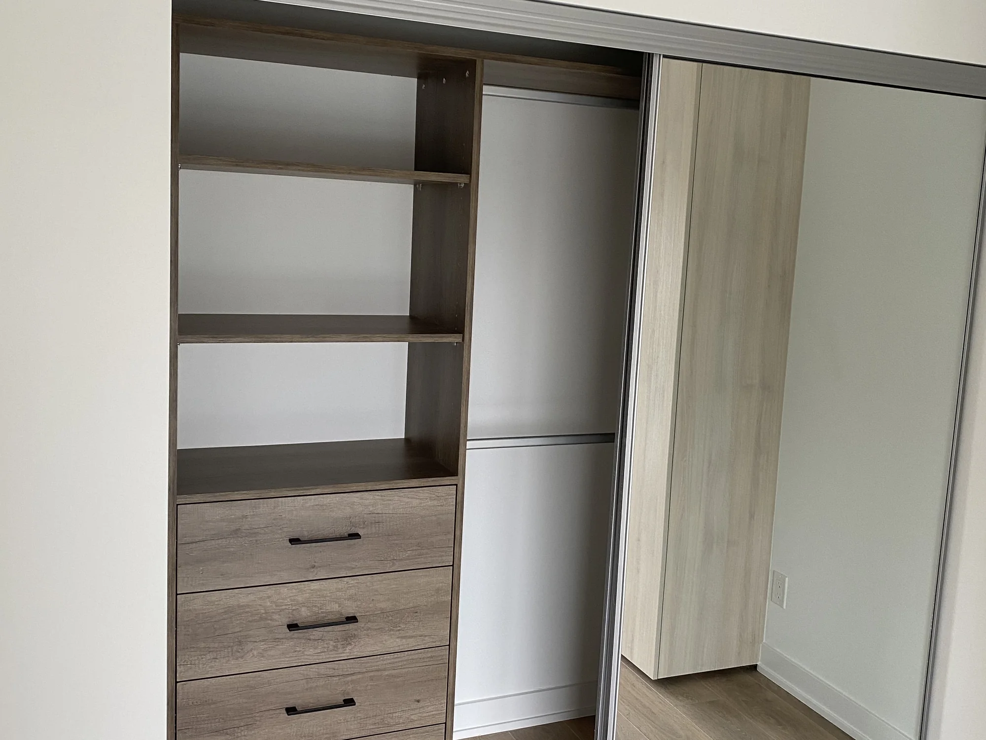 Completed reach-in closet with drawers, open shelves, hanging space, and sliding doors.