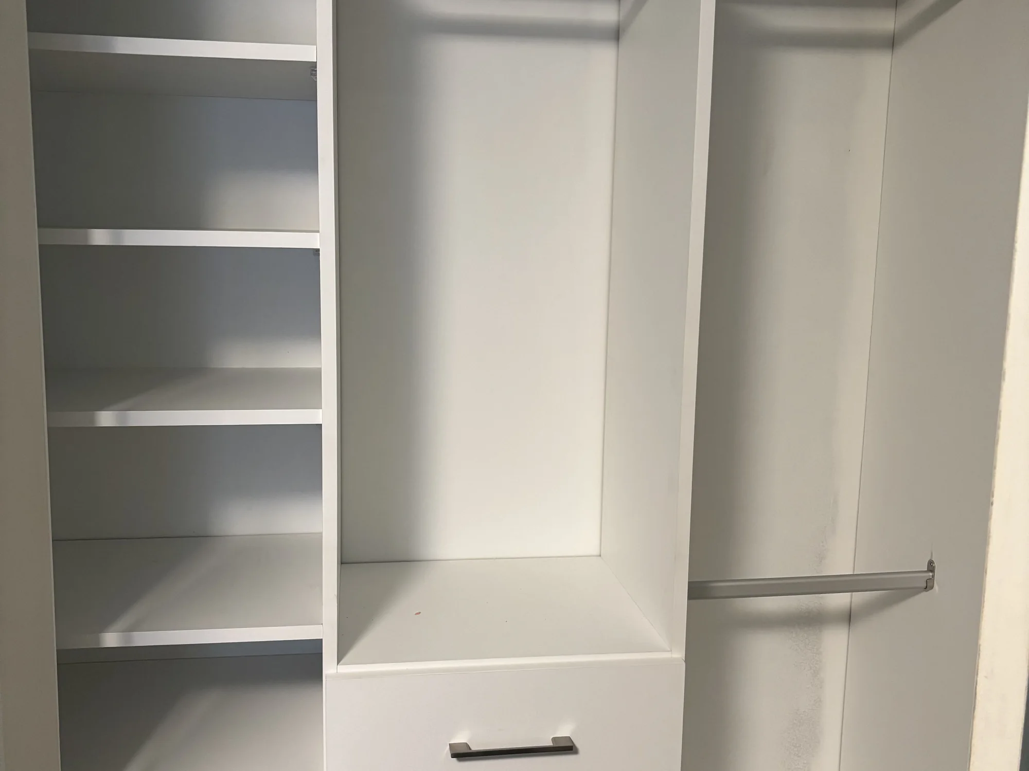 Completed reach-in closet organized around shelves and hanging rails.