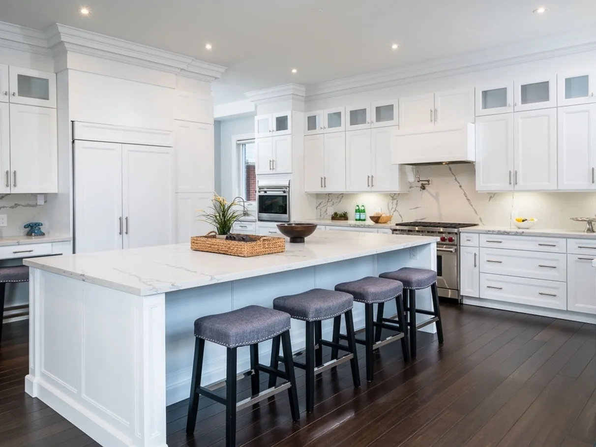 Completed Transitional kitchen with framed white cabinetry, a large clean-lined island, moderate crown detail, and glass-front cabinets.