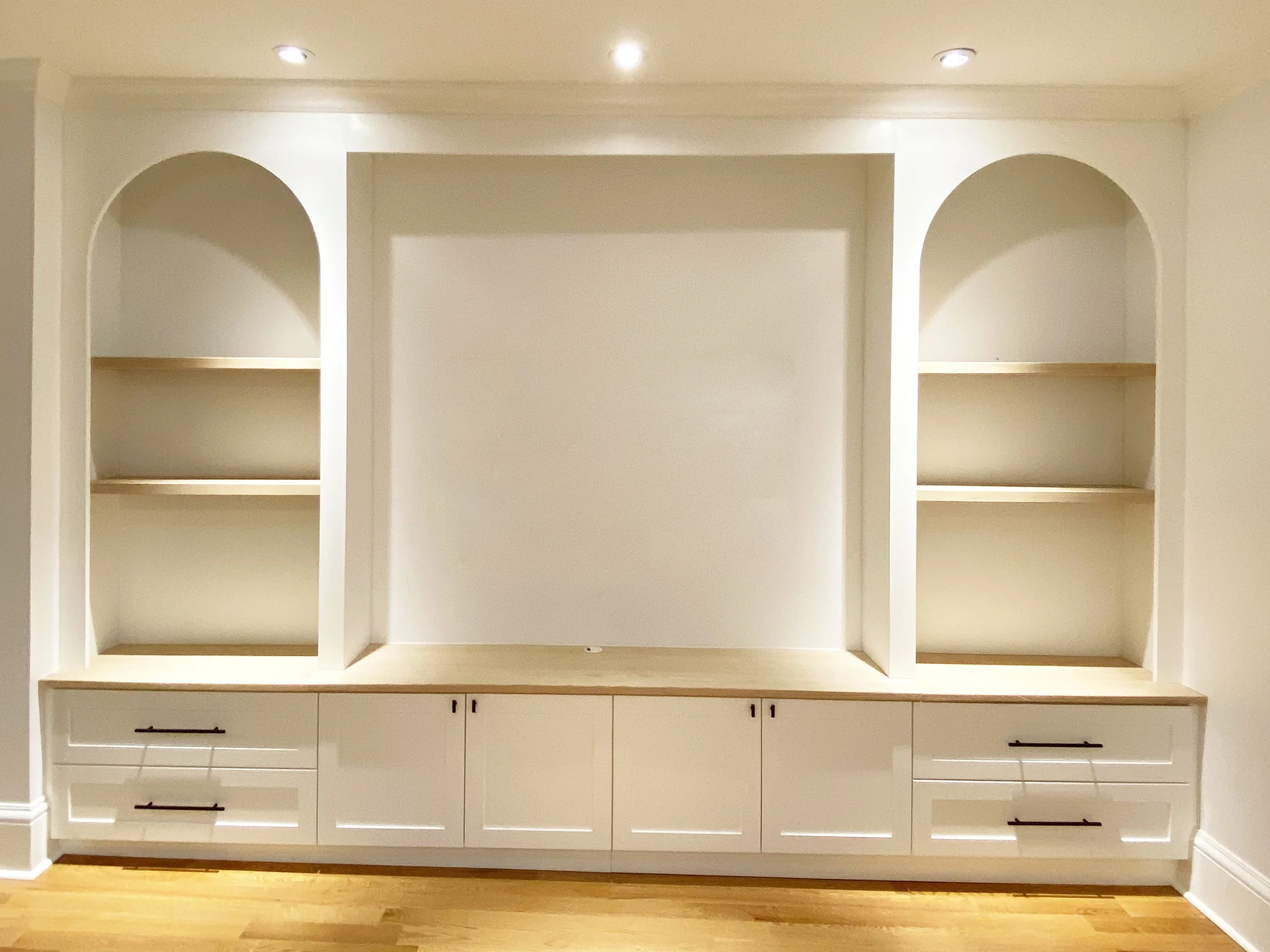 Completed entertainment wall with illuminated arches, drawers, and base cabinets.