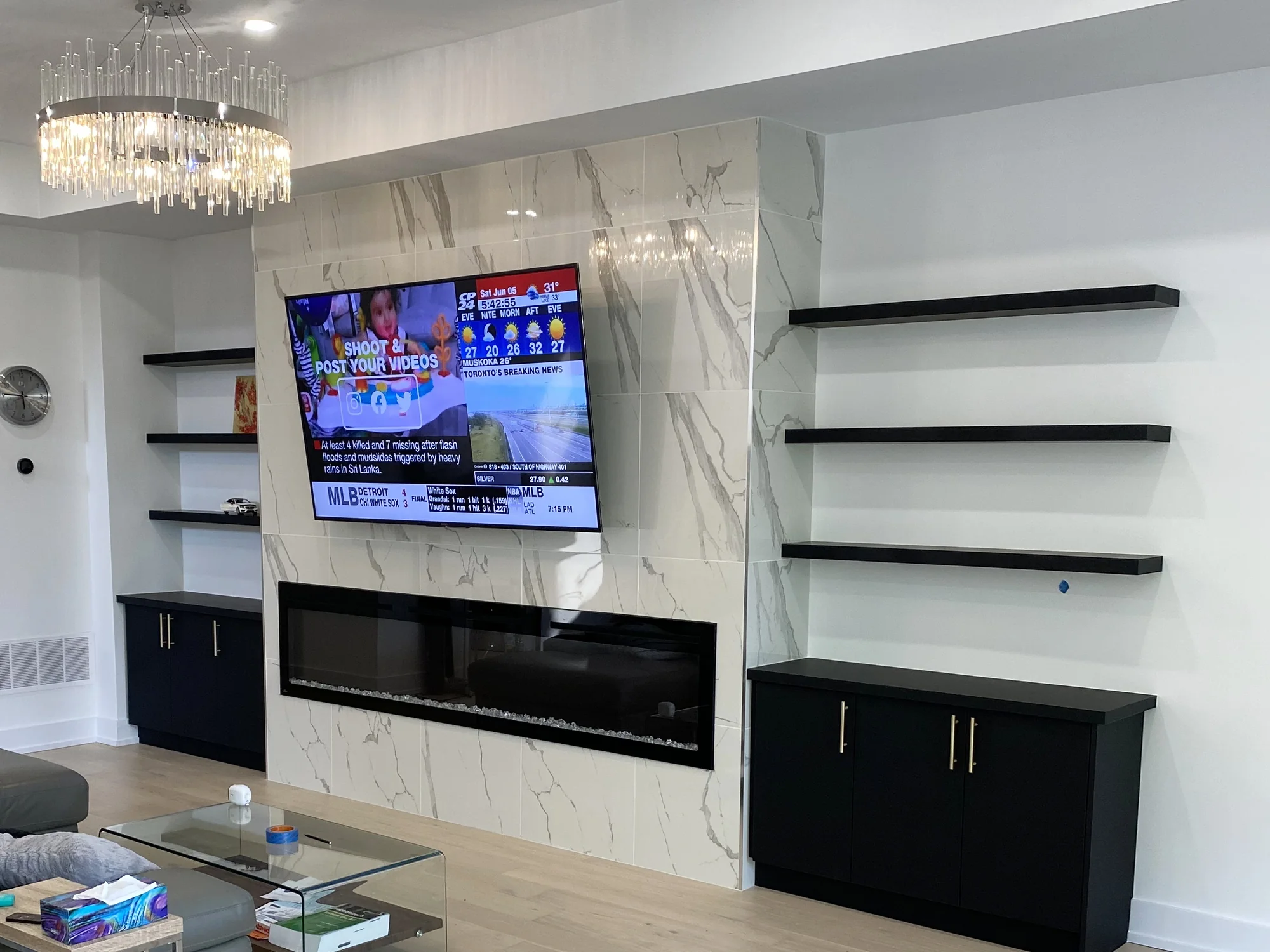 Completed fireplace media wall with stone, shelves, and black base cabinets.
