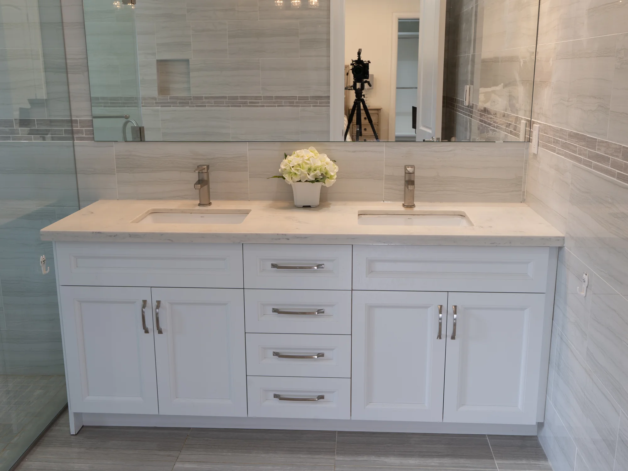 Completed white double vanity with drawers, cabinet doors, and stone counters.
