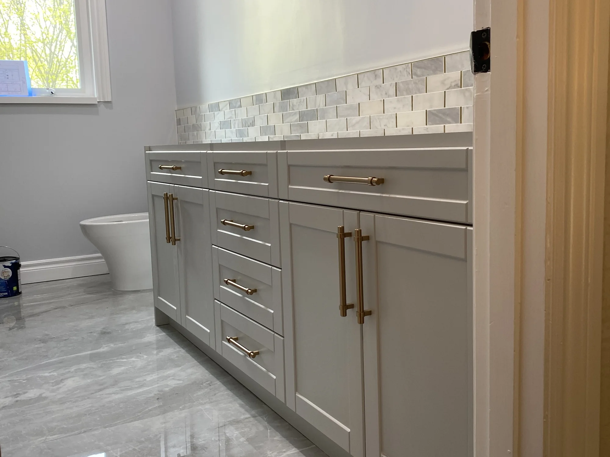 Completed grey shaker vanity with drawers, doors, and brass hardware.