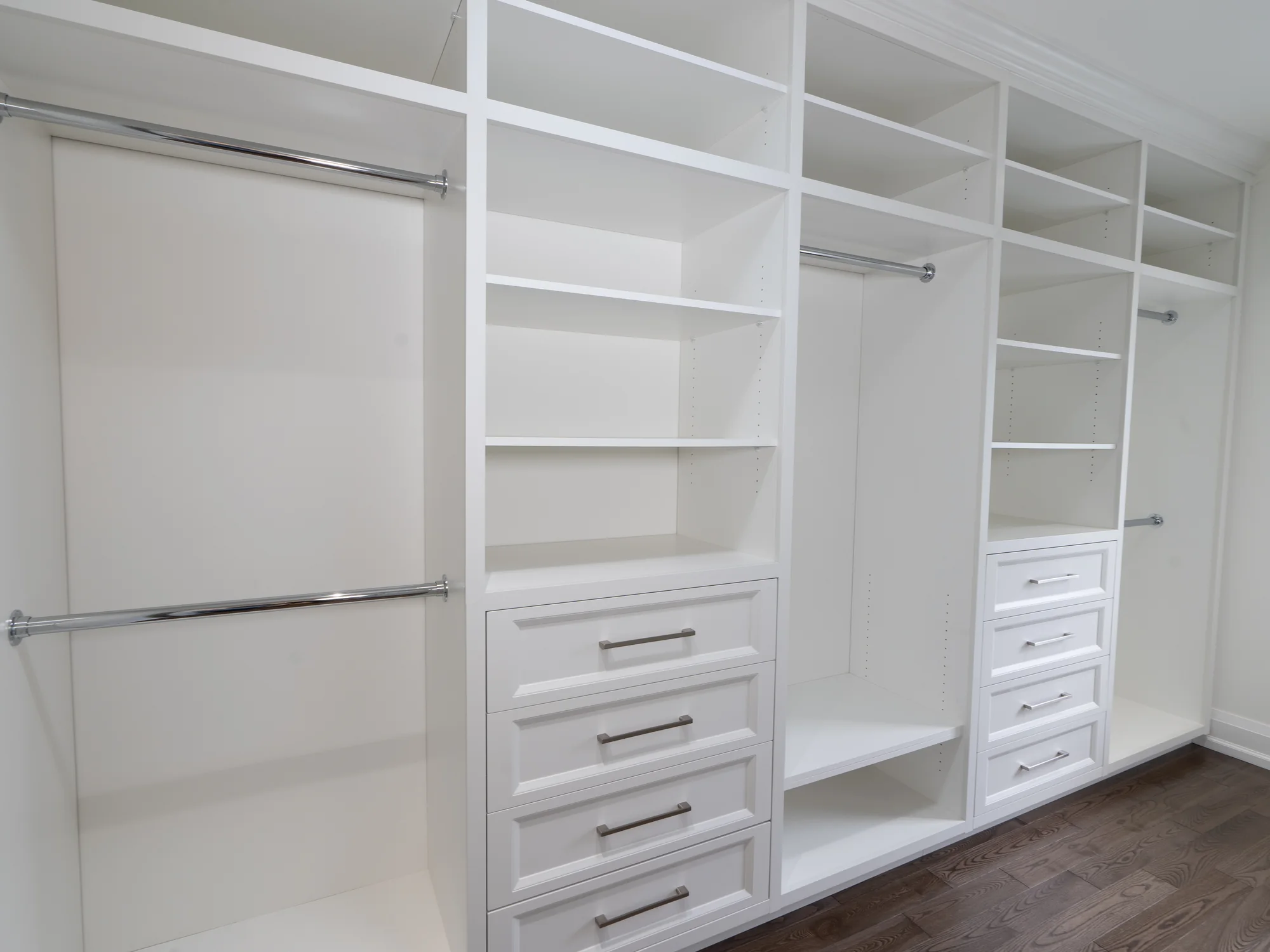 Completed white walk-in closet with fitted hanging space, shelves, and drawers.