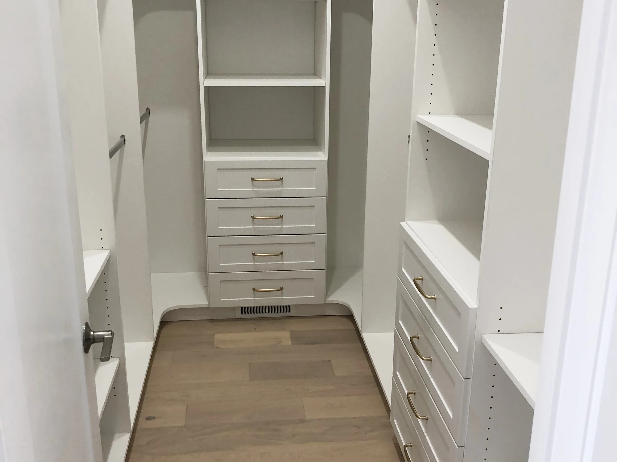 Completed U-shaped white walk-in closet with drawers, shelves, and hanging rails.