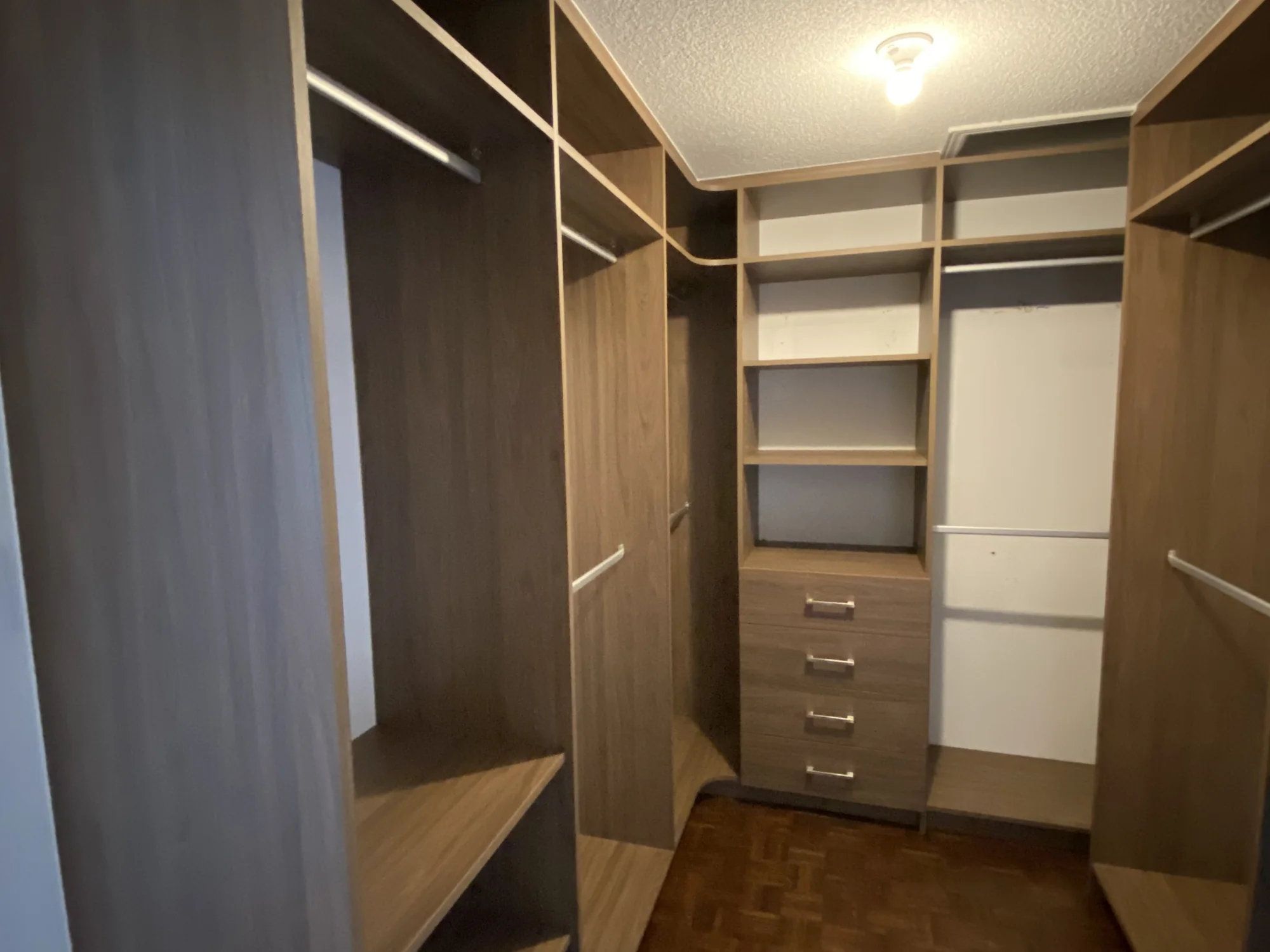 Completed dark wood walk-in closet with open storage and integrated drawers.