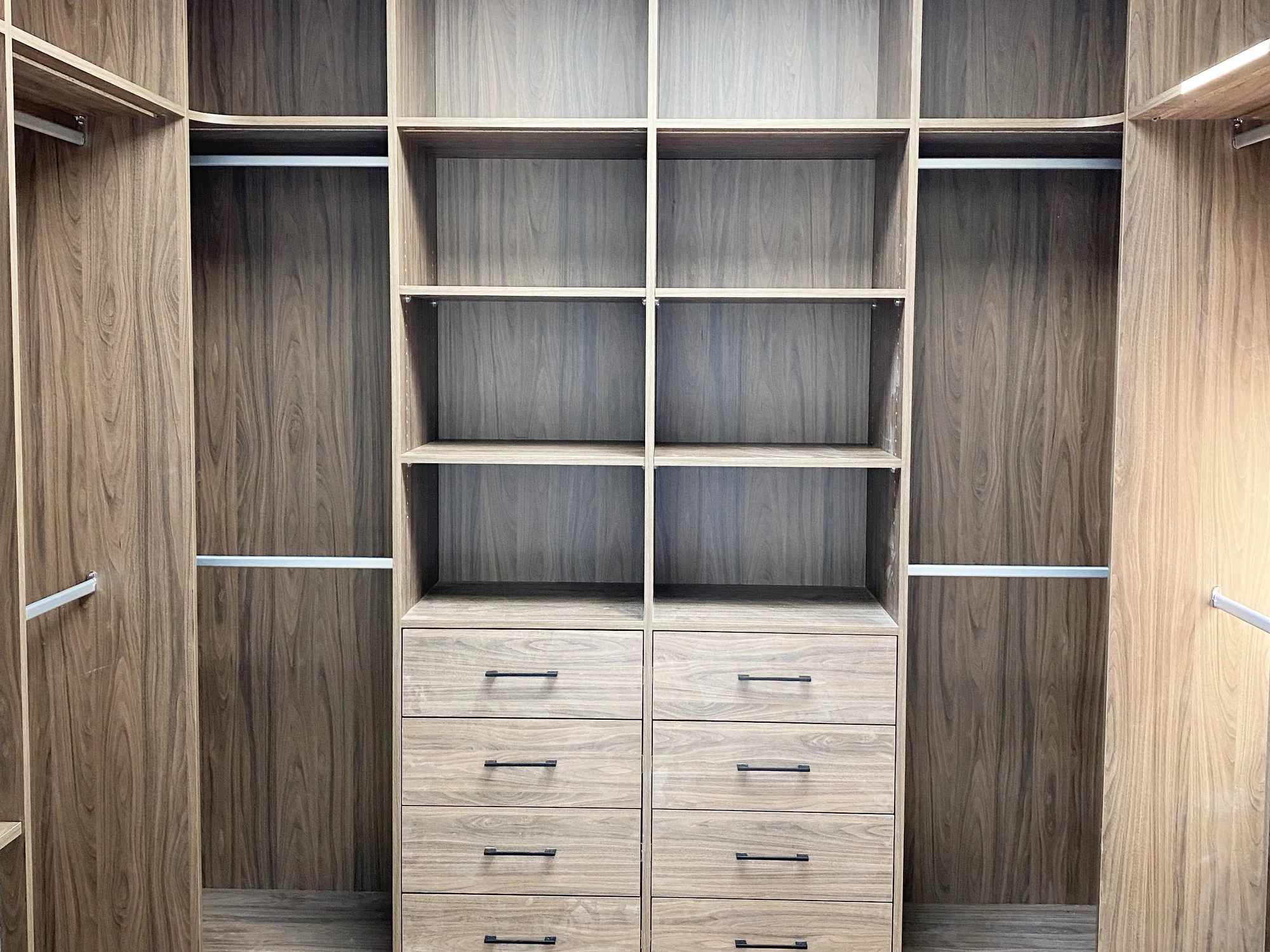 Completed wood-tone walk-in closet with coordinated shelving, hanging rails, and drawers.