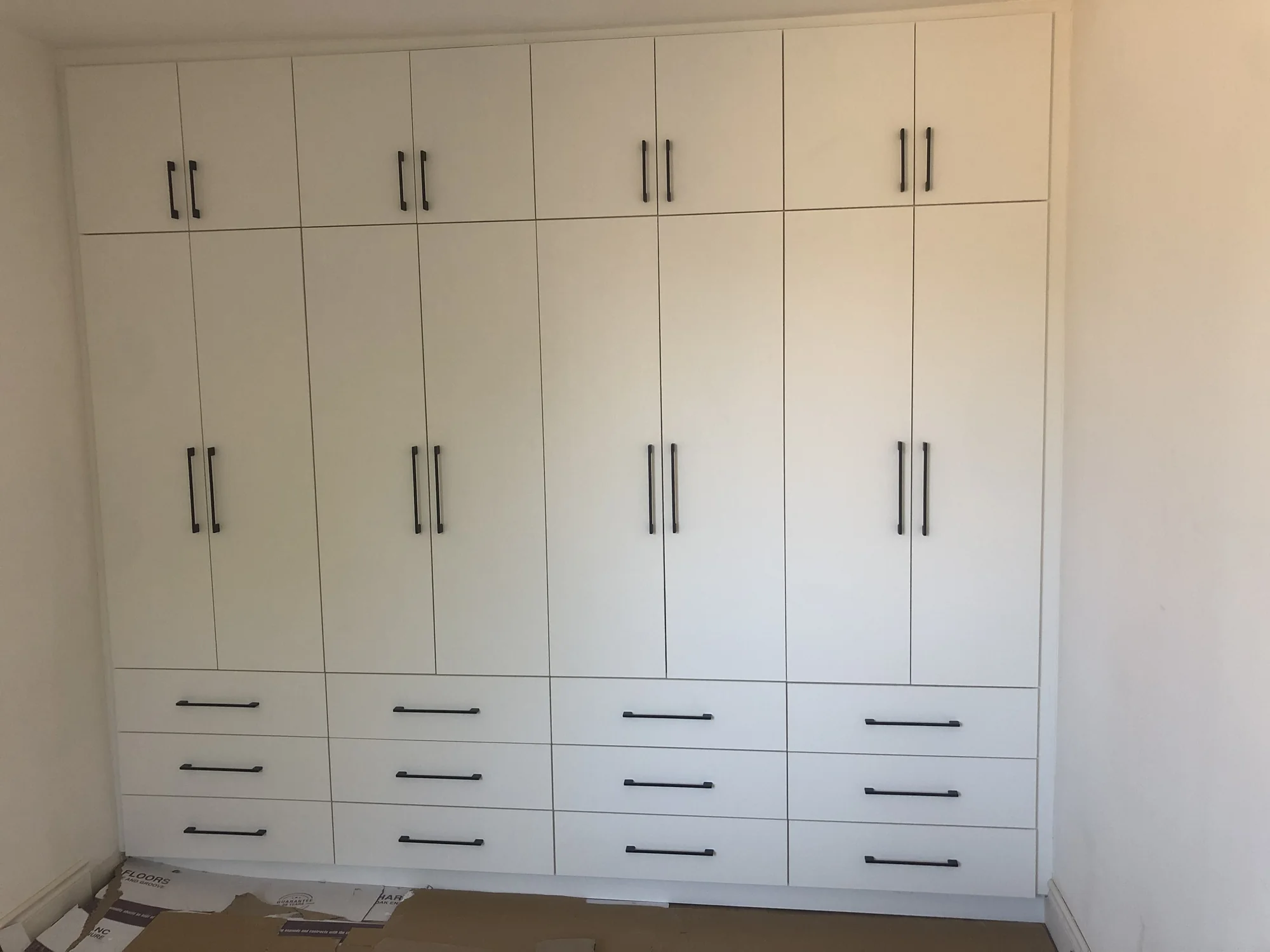 Completed full-wall white wardrobe with coordinated drawers and doors.