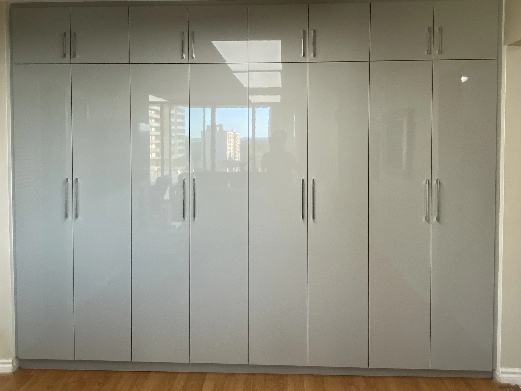 Completed high-gloss white wardrobe with full-height doors.