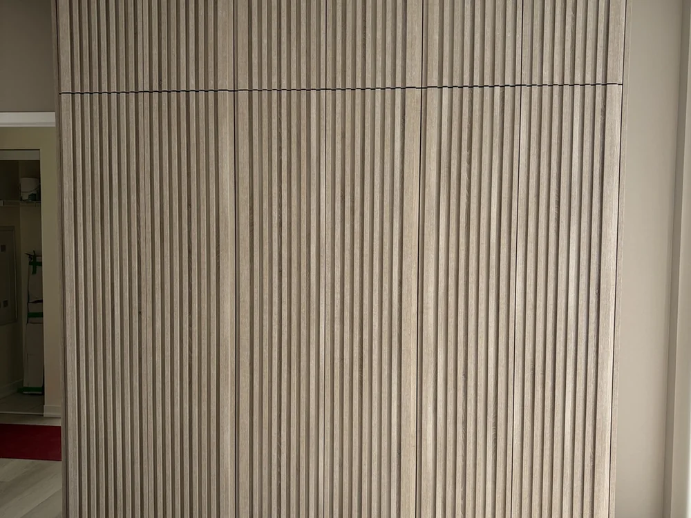 Completed wardrobe with vertically slatted full-height doors.