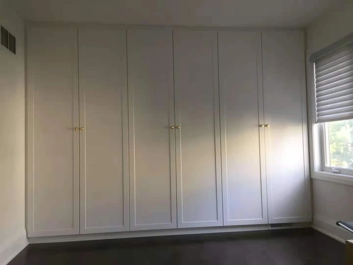 Completed white wardrobe with full-height shaker doors.