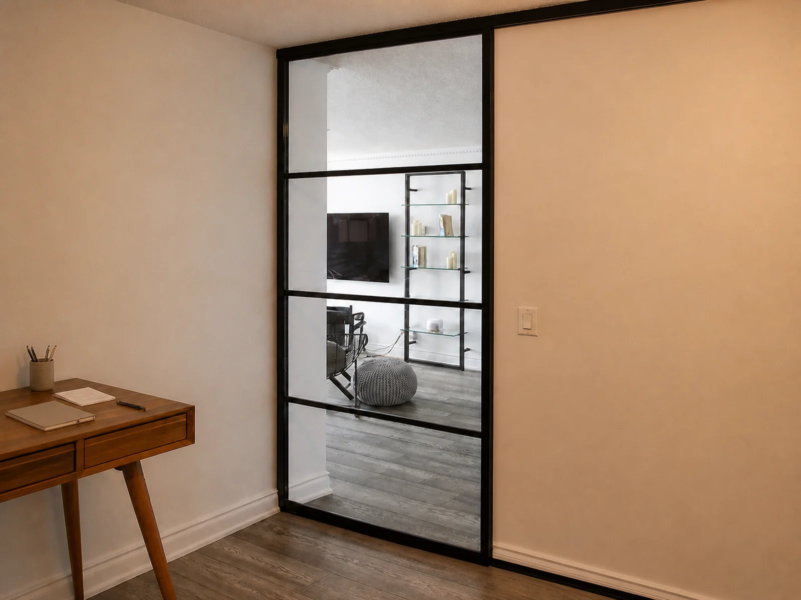 Single black-framed clear glass sliding door closing a compact den or work area.